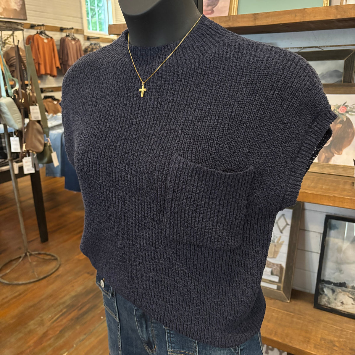 Navy knit sweater top with gold cross necklace on mannequin in the boutique