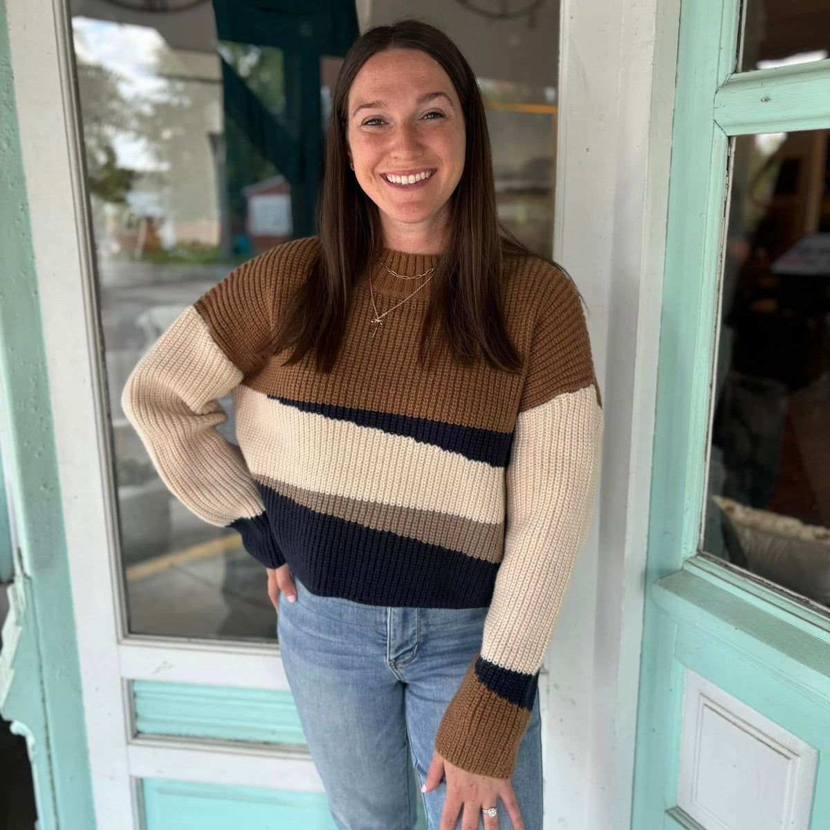 Woman wearing a brown, cream and navy color-block striped sweater