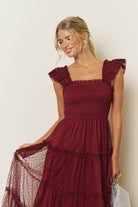 Model twirling in a burgundy smocked tiered tulle midi dress