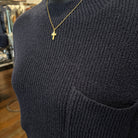 Close-up of navy ribbed knit sweater with gold cross necklace