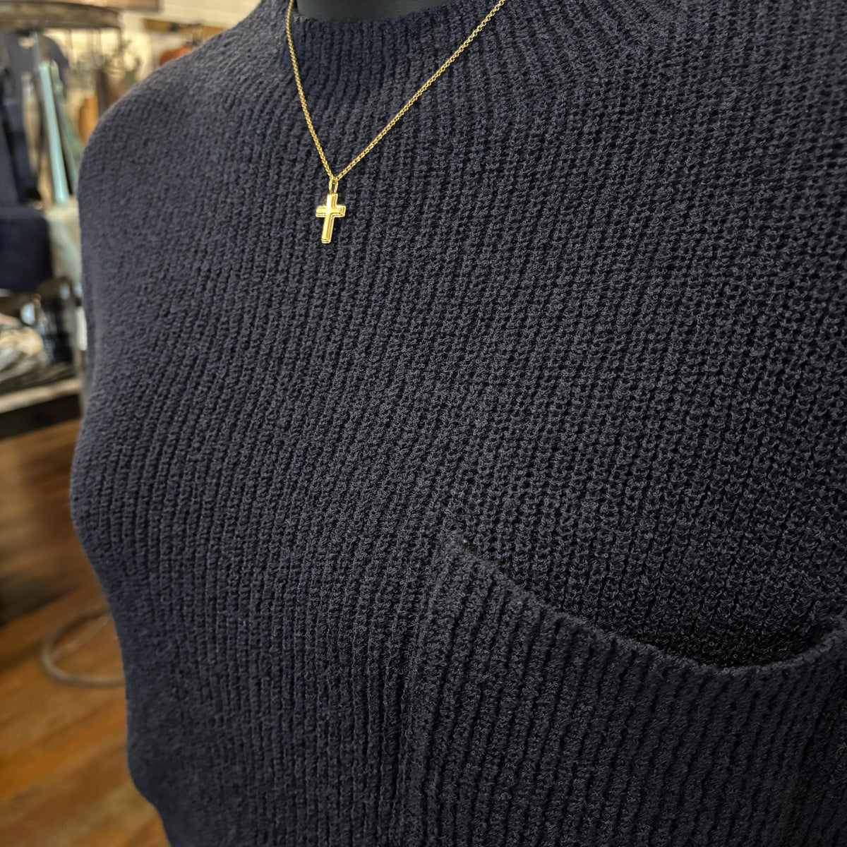 Close-up of navy ribbed knit sweater with gold cross necklace